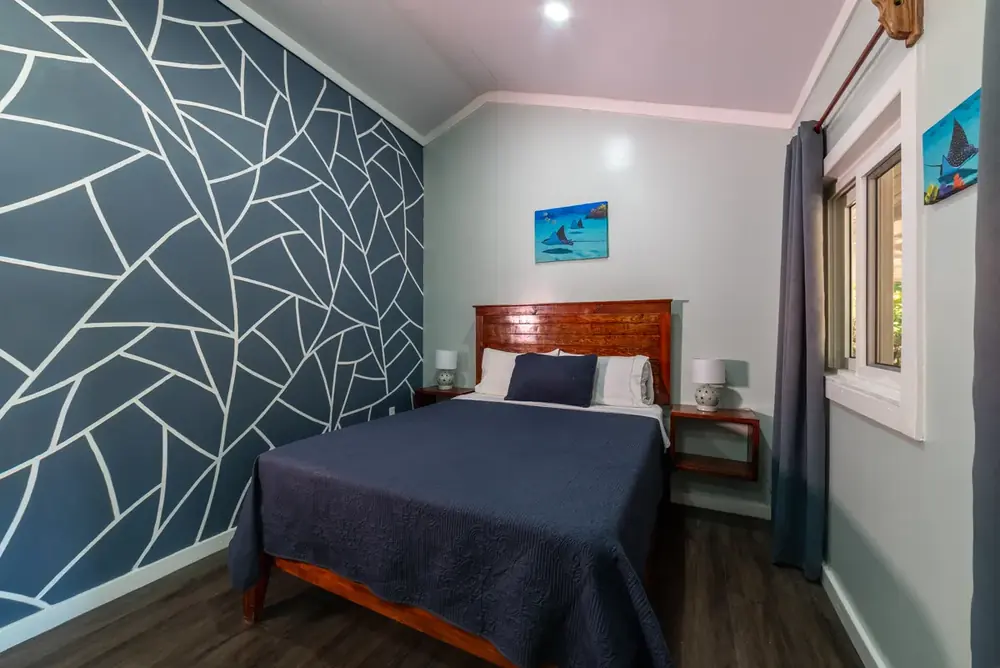 Studio room with queen bed, navy linens and reef artwork